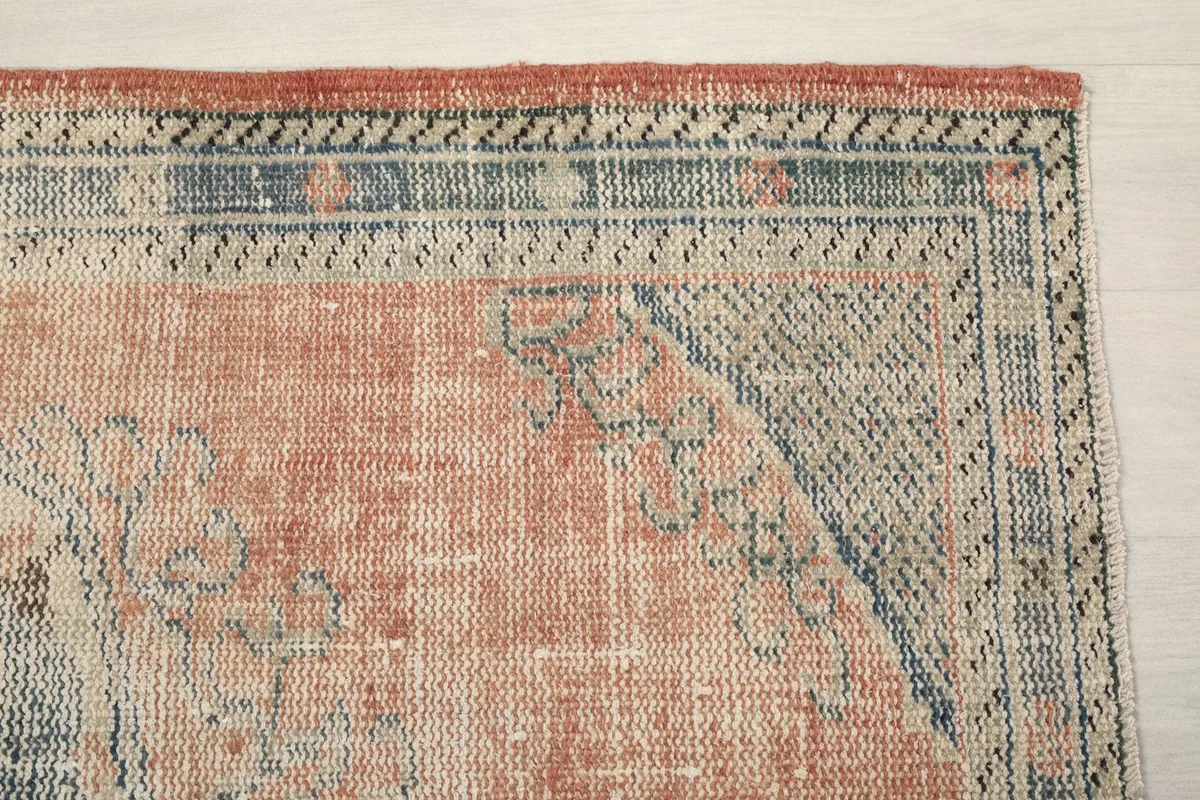 Detail of the rug's border with geometric patterns in blue, gray, and ivory