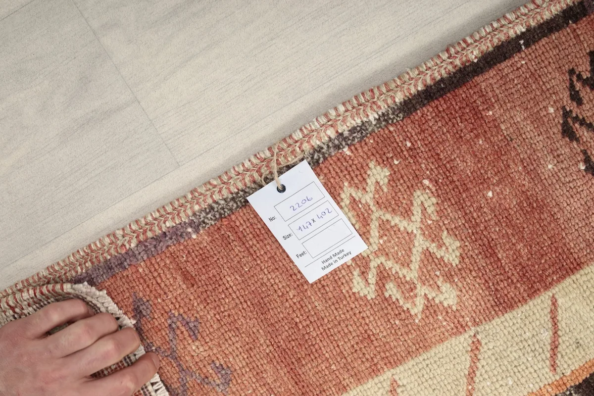 Hand holding a product tag against the rug's border, showing branding information.