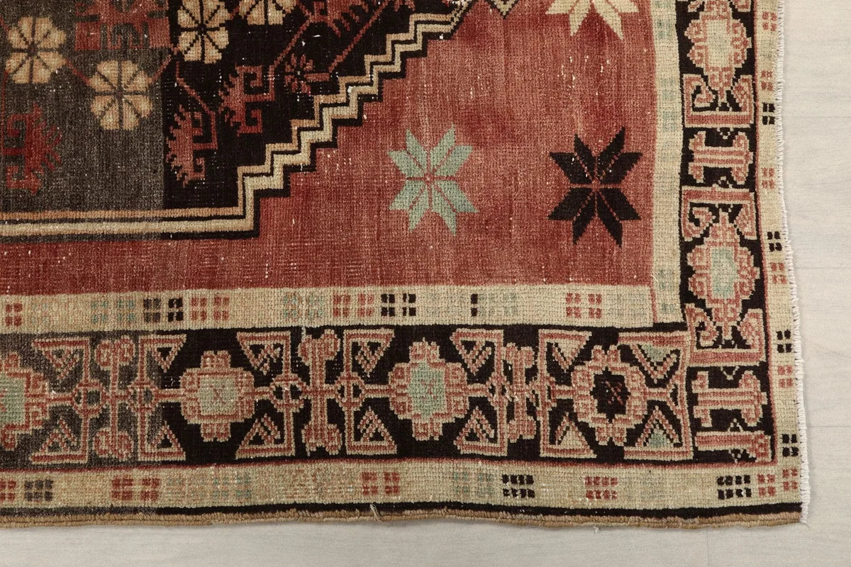 Detailed view of the rug's corner with geometric border and main field patterns