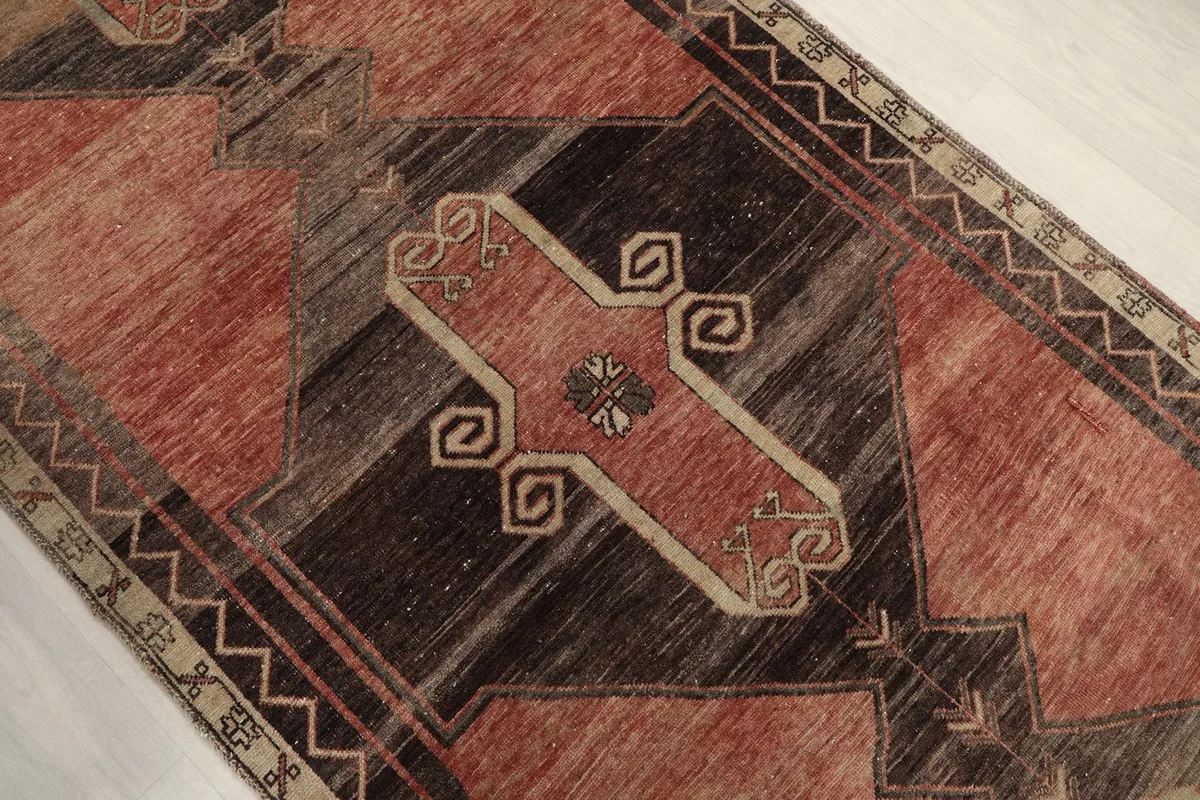 Detailed view of a central geometric motif in rust, brown, and beige on the runner rug