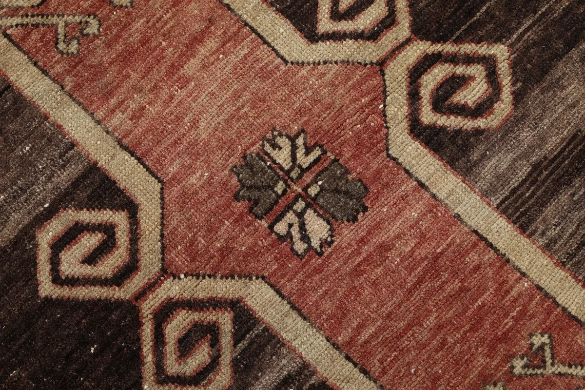 Very close detail of the rug's intricate knotting and a small floral-like motif