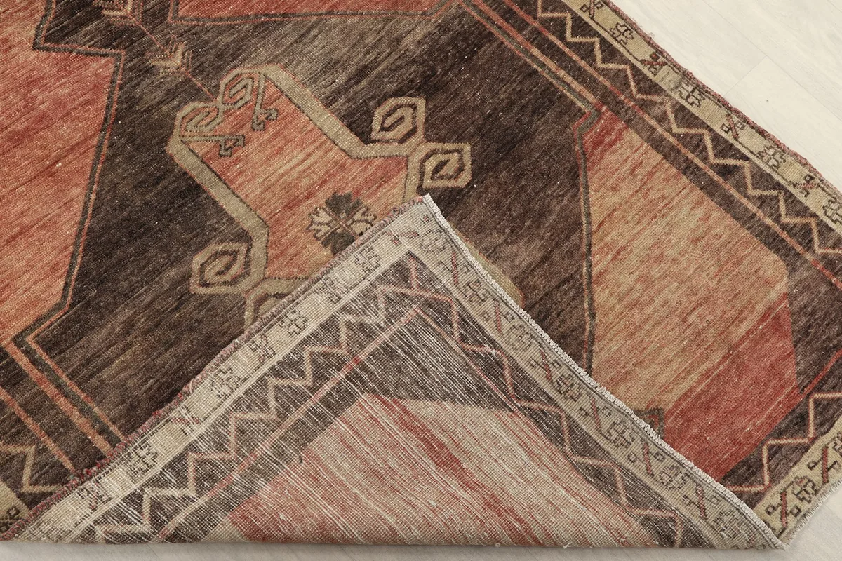 Corner of the rug folded to show the cotton foundation and reverse side of the hand-knotting