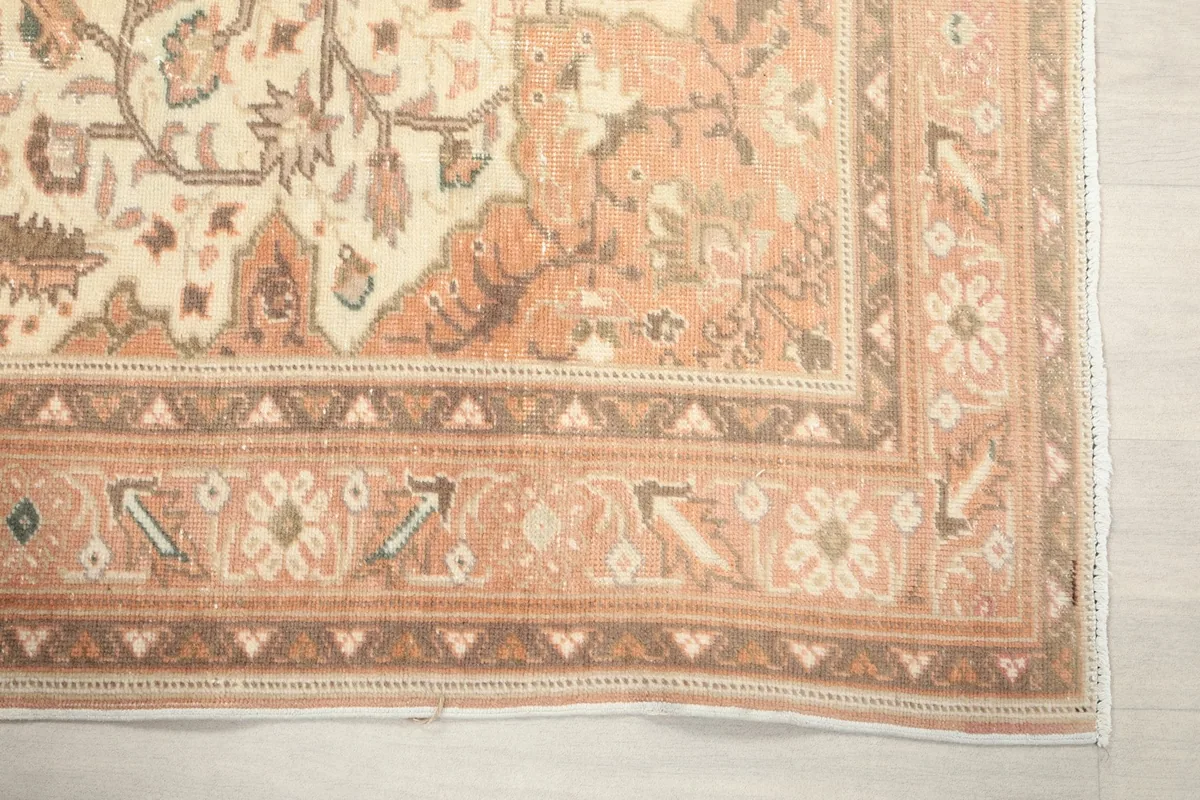 Detailed view of the rug's corner and border design with geometric patterns in rust and brown tones.