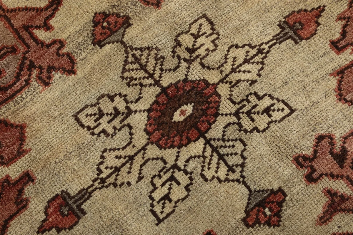 Extreme close-up on the intricate central design of the medallion with brown and ivory threads