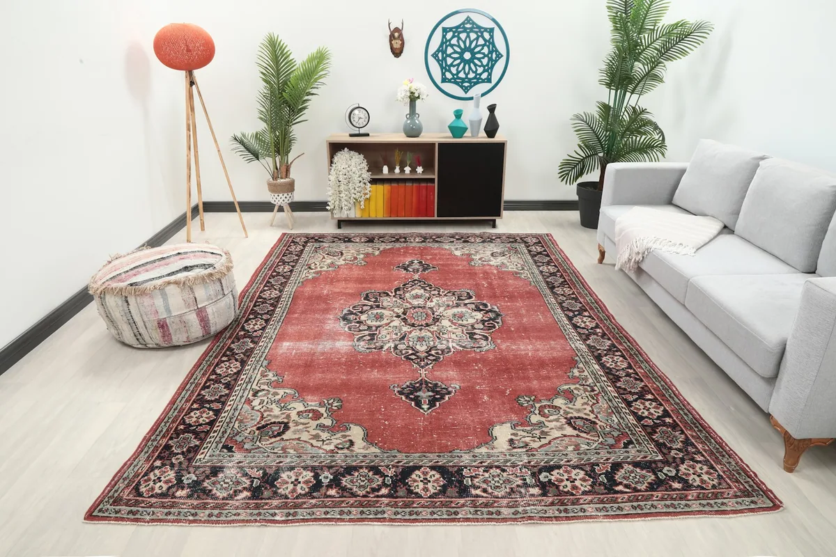 Vintage red rug displayed in a living room setting with a sofa and plants