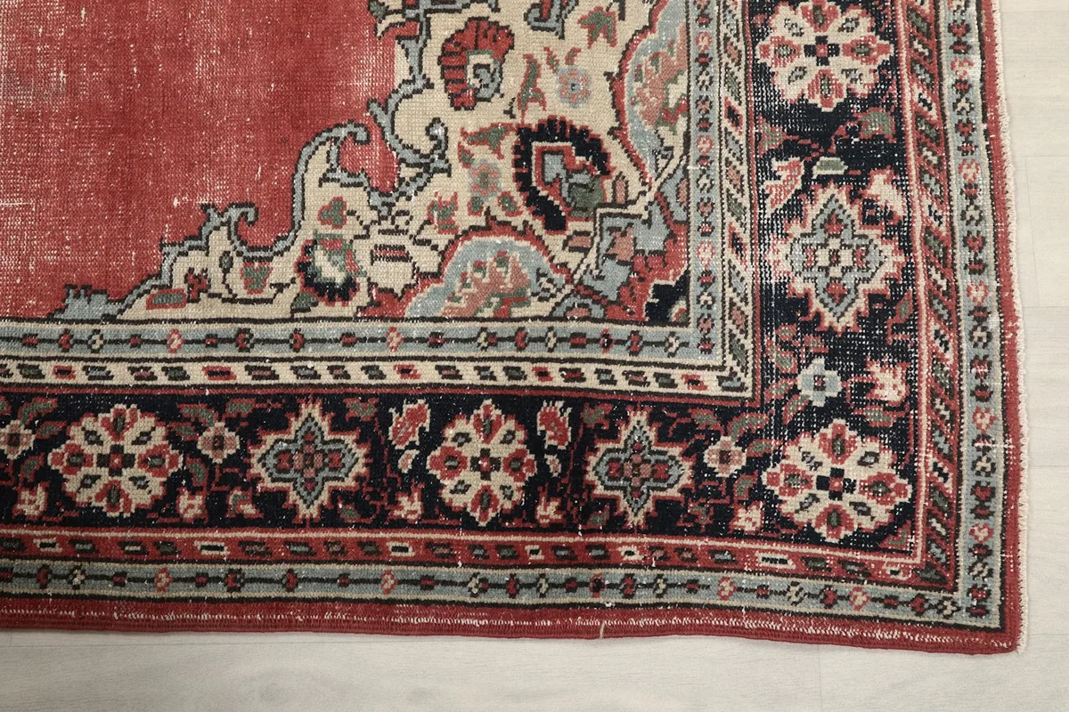Detailed view of the navy and beige border pattern and corner of the vintage rug