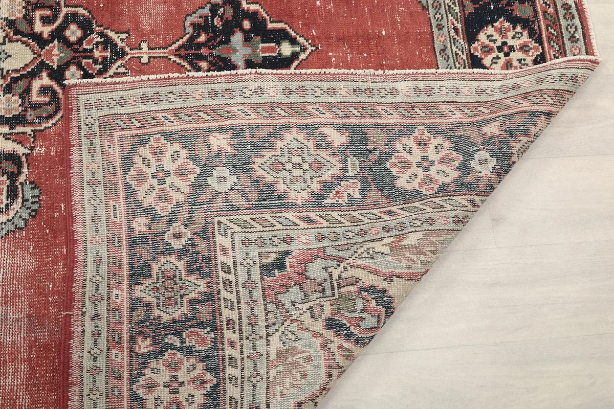 Corner of the rug folded back, showing the back of the rug and the border details