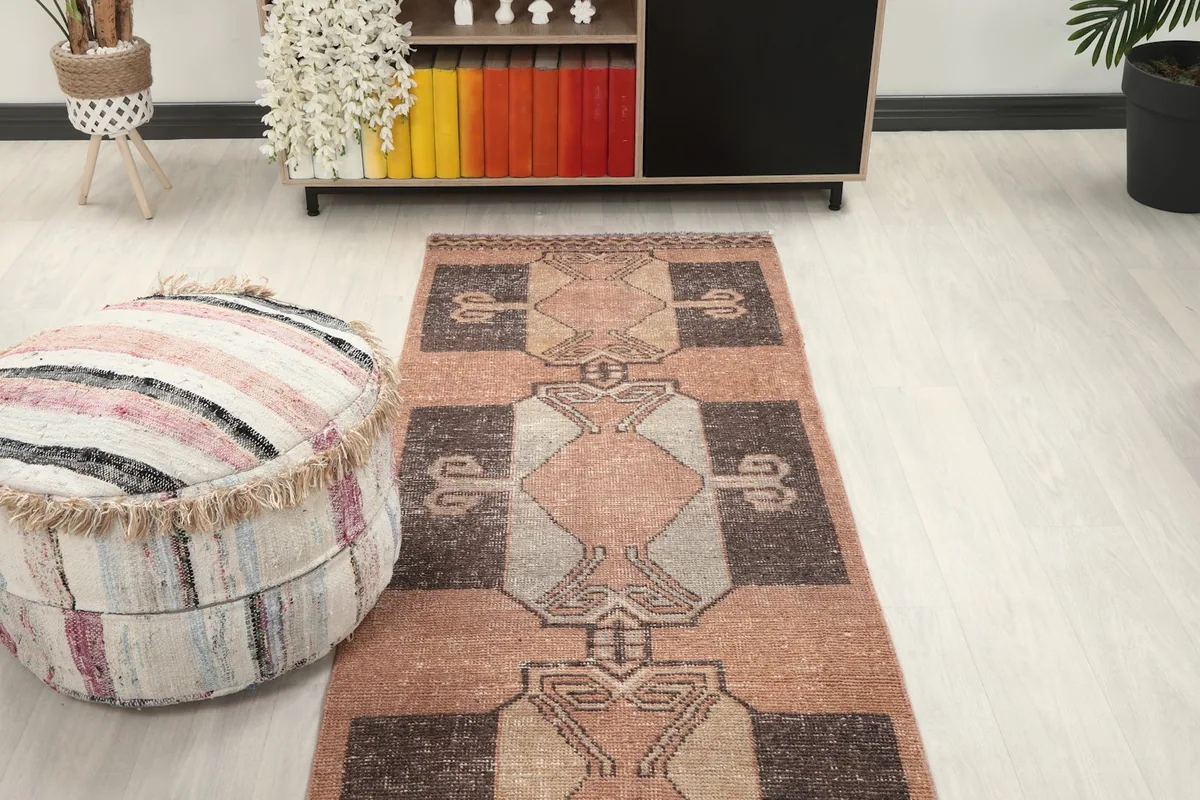 Runner rug viewed from above, positioned between a pouf and a cabinet, showcasing its full pattern