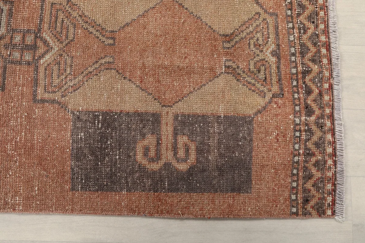 Detailed view of one end of the runner rug, showing the border pattern and a central geometric motif