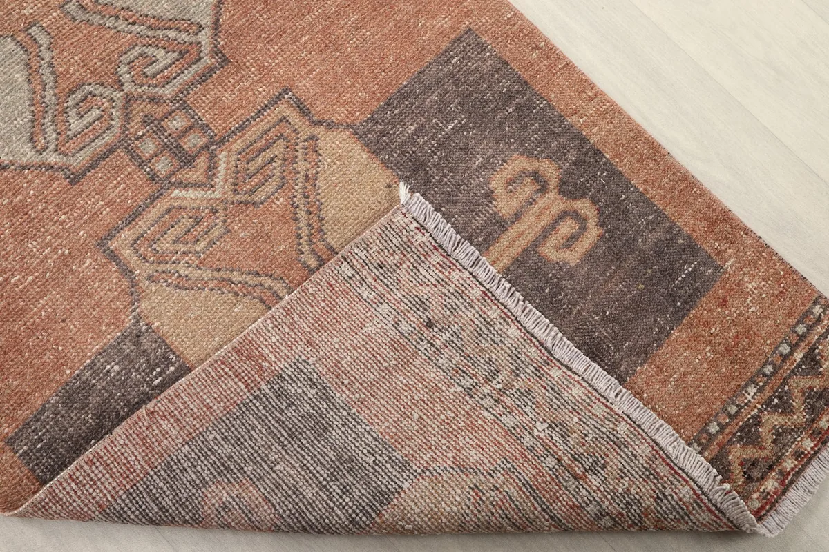 Folded corner of the runner rug revealing the cotton foundation and the reverse side of the hand-knotting