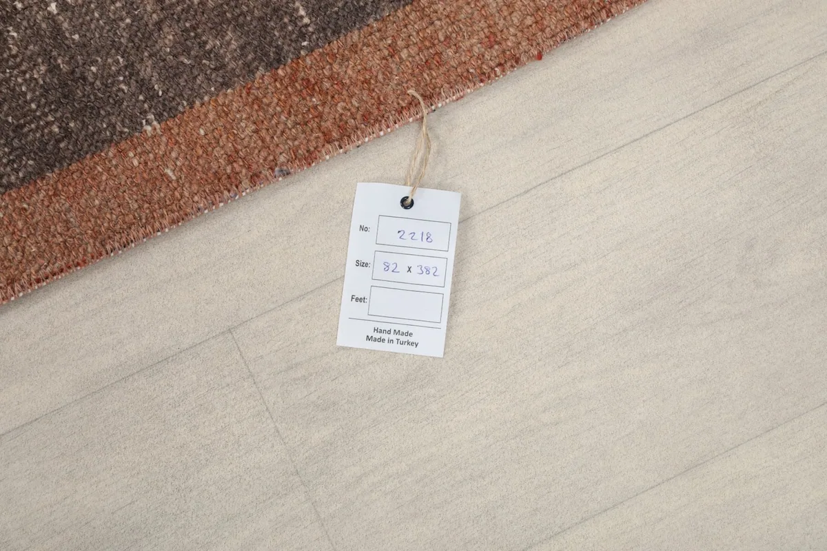 Tag with rug dimensions (82x382 cm) and origin information, placed on the floor next to the rug