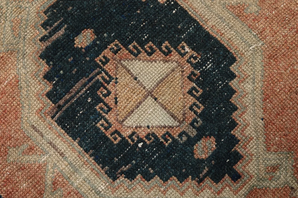 Extreme close-up of a navy motif within the rug, showcasing the hand-knotted texture and wool pile