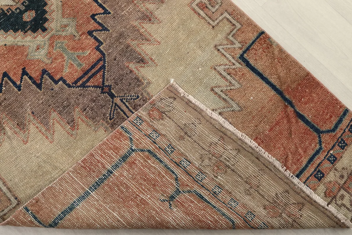 Flipped corner of the rug revealing the hand-knotted cotton foundation and the reverse of the pile