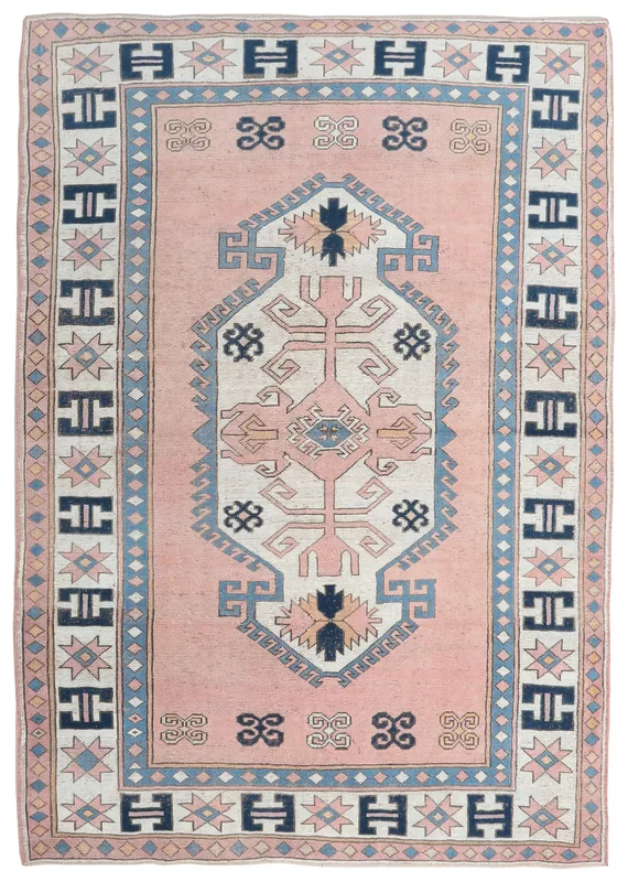 Full overhead view of the vintage pink and navy geometric medallion rug on a white background