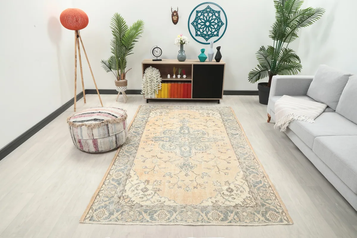 Beige and gray floral medallion rug in a modern living room setting with a sofa and pouf
