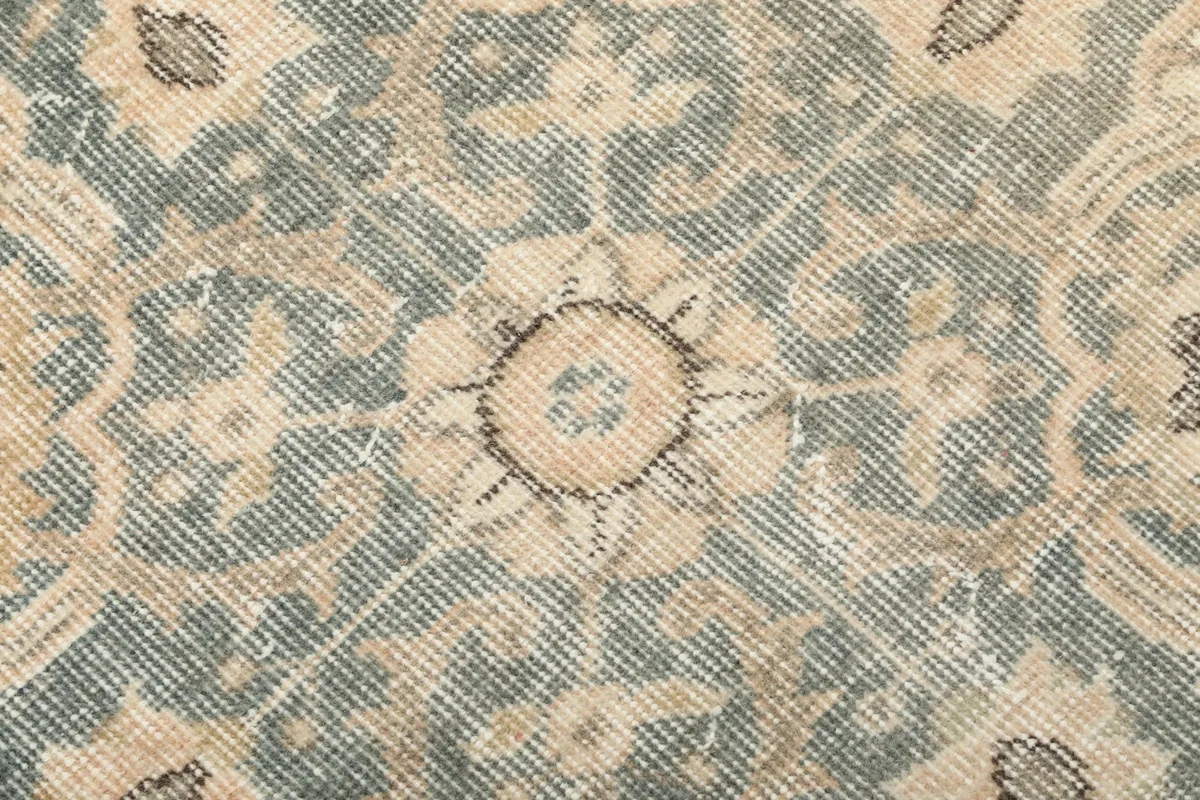 Extreme close-up of the hand-knotted wool pile showing texture and color variations within the gray motif