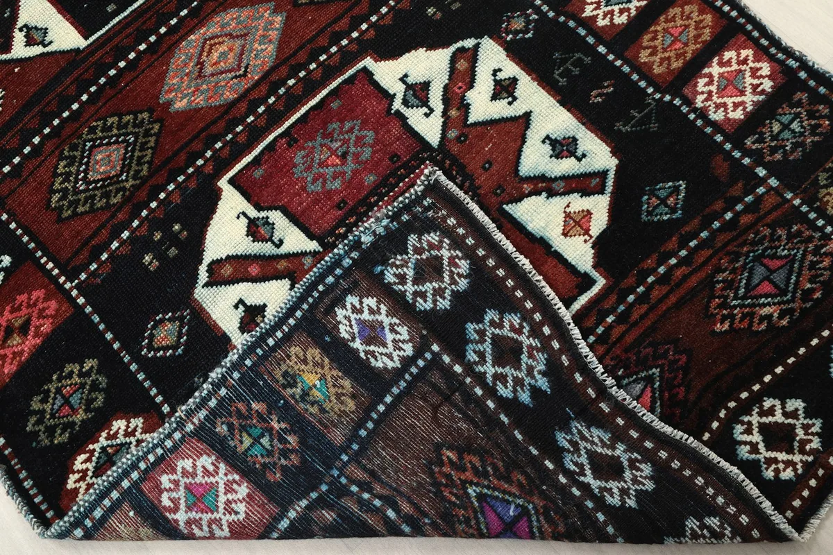 View of the underside of a corner of the rug, revealing the hand-knotted cotton foundation