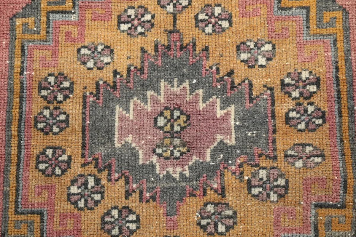 Close-up of the central motif within the medallion, showcasing faded colors and wool texture.