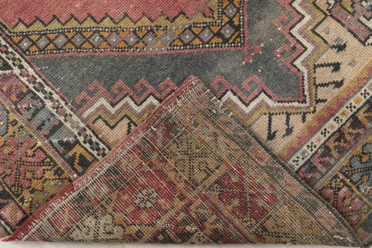 Folded corner of the rug revealing the backside of the hand-knotted wool pile and cotton foundation.