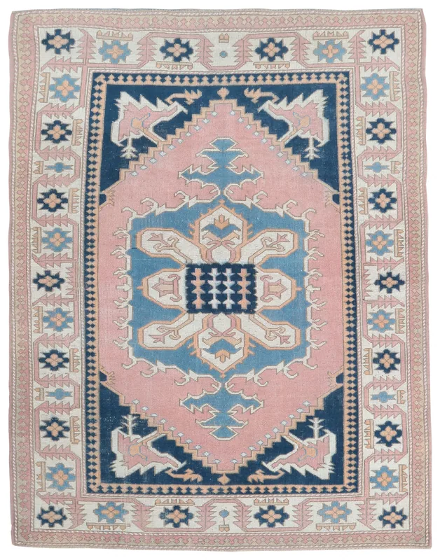 Full overhead view of the vintage pink and navy Anatolian area rug on a white background.