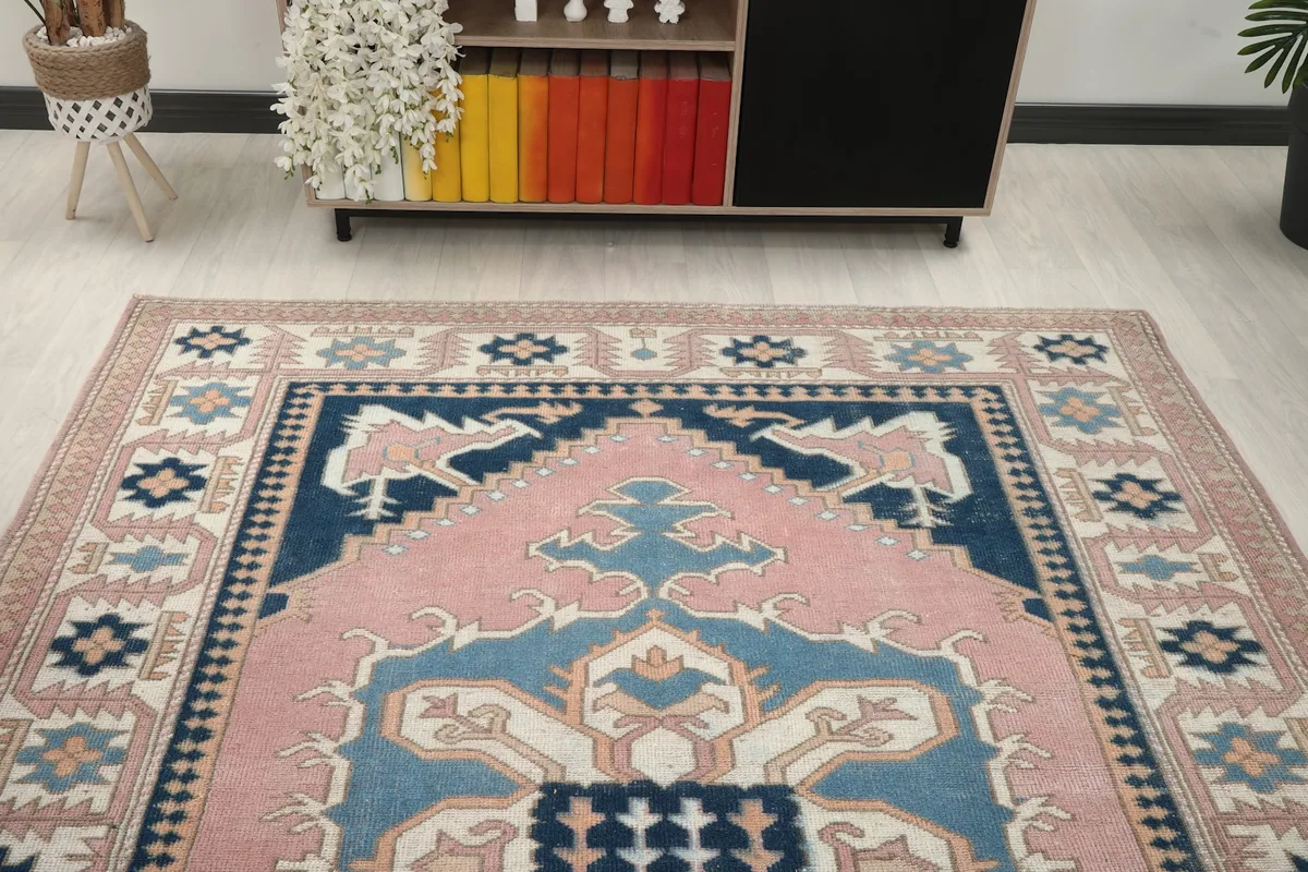 Overhead angle view capturing the top portion of the pink and navy Anatolian rug in a room.