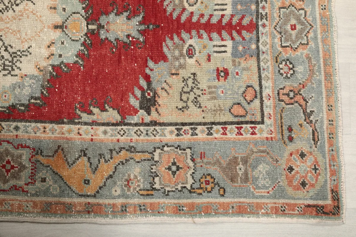 Detailed view of the rug's border showing gray, orange, and gold tribal motifs