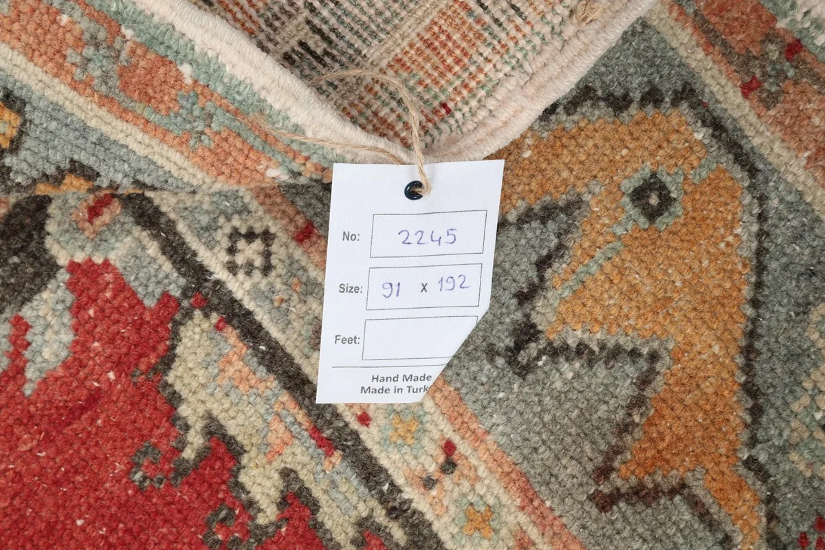 Back of the rug with a label showing size and origin, confirming hand-knotted wool on cotton