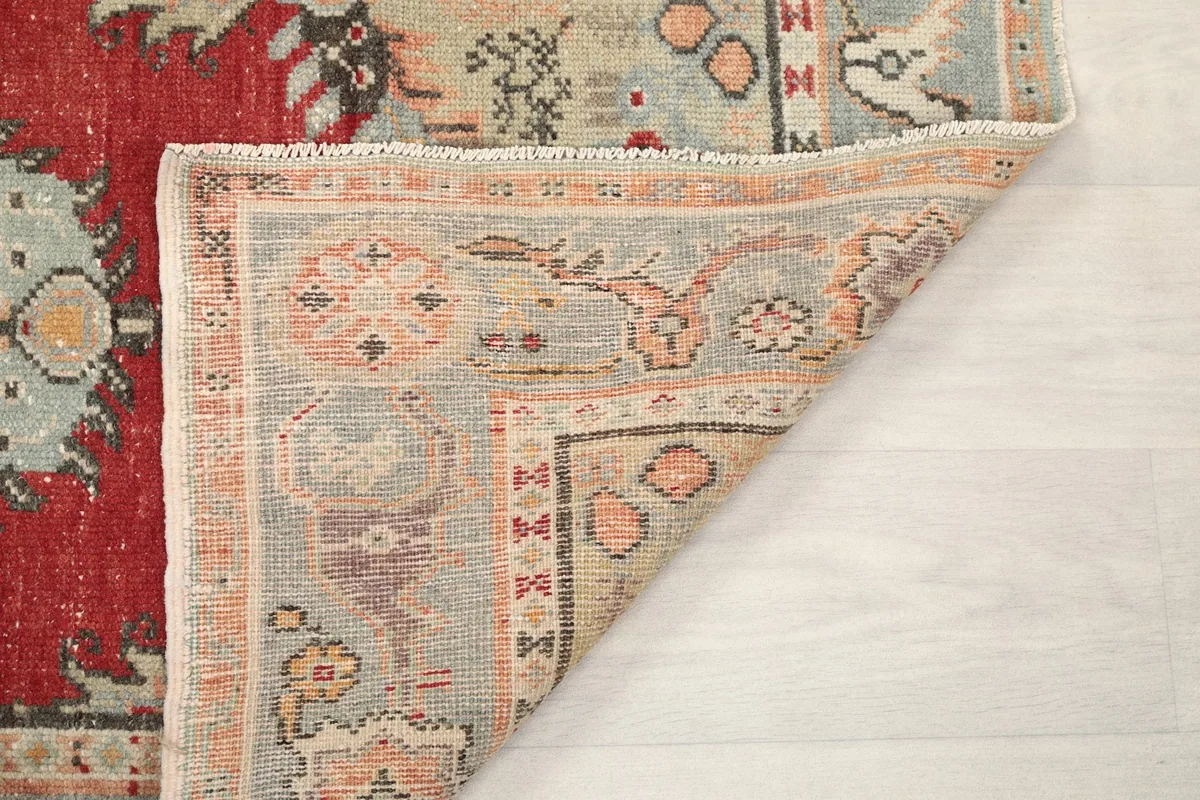 Opposite corner of the rug folded to show the hand-knotted construction and fringe