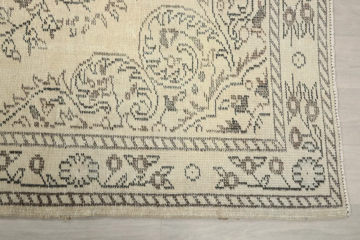 Detailed view of the intricate gray border design on the ivory field