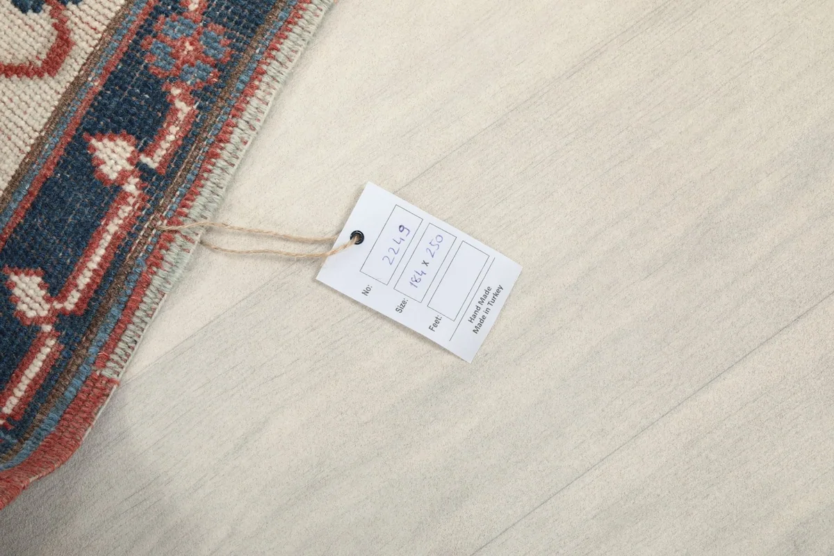Product tag attached to the rug, showing size and origin details, on a light floor