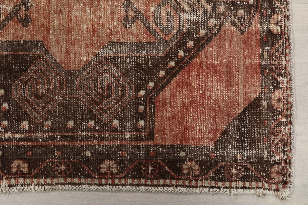 Detailed view of the rug's end, showcasing the tribal motifs, border design, and subtle wear.