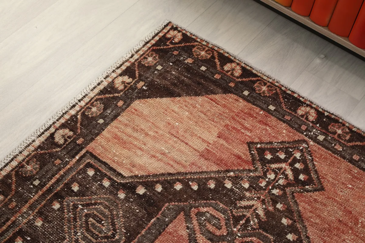 Close-up of the rug's corner, detailing the charcoal border and the intricate patterns.