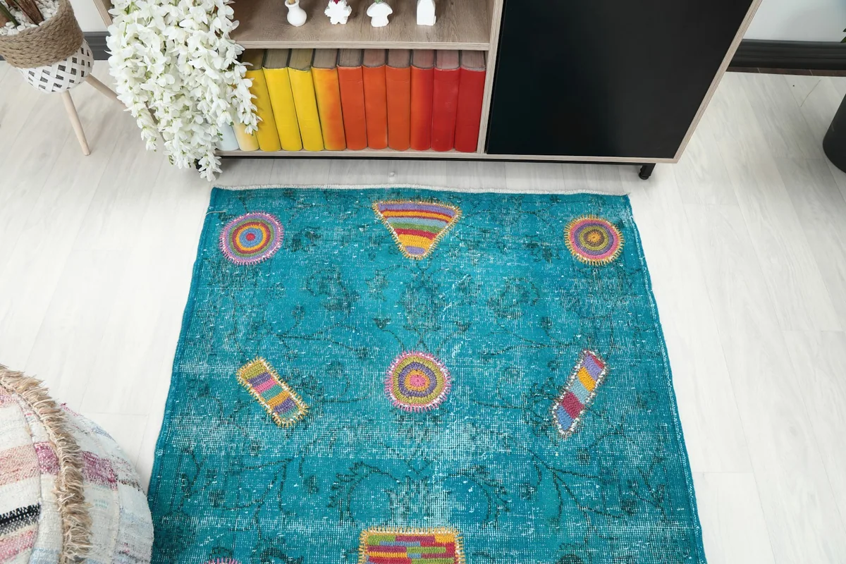 Overhead shot of the blue rug, showcasing the arrangement of its multicolor geometric elements.
