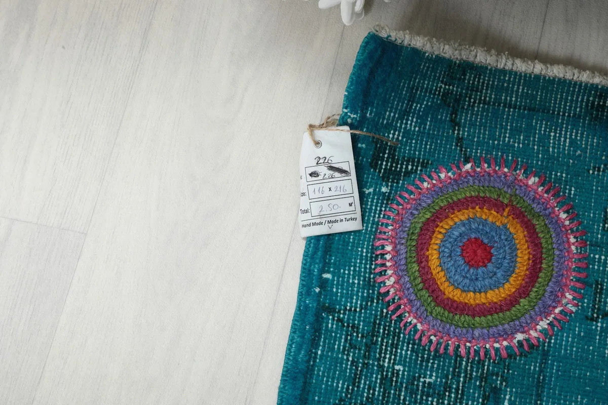 Photo showing the rug's care tag attached to a corner, next to a multicolor motif.