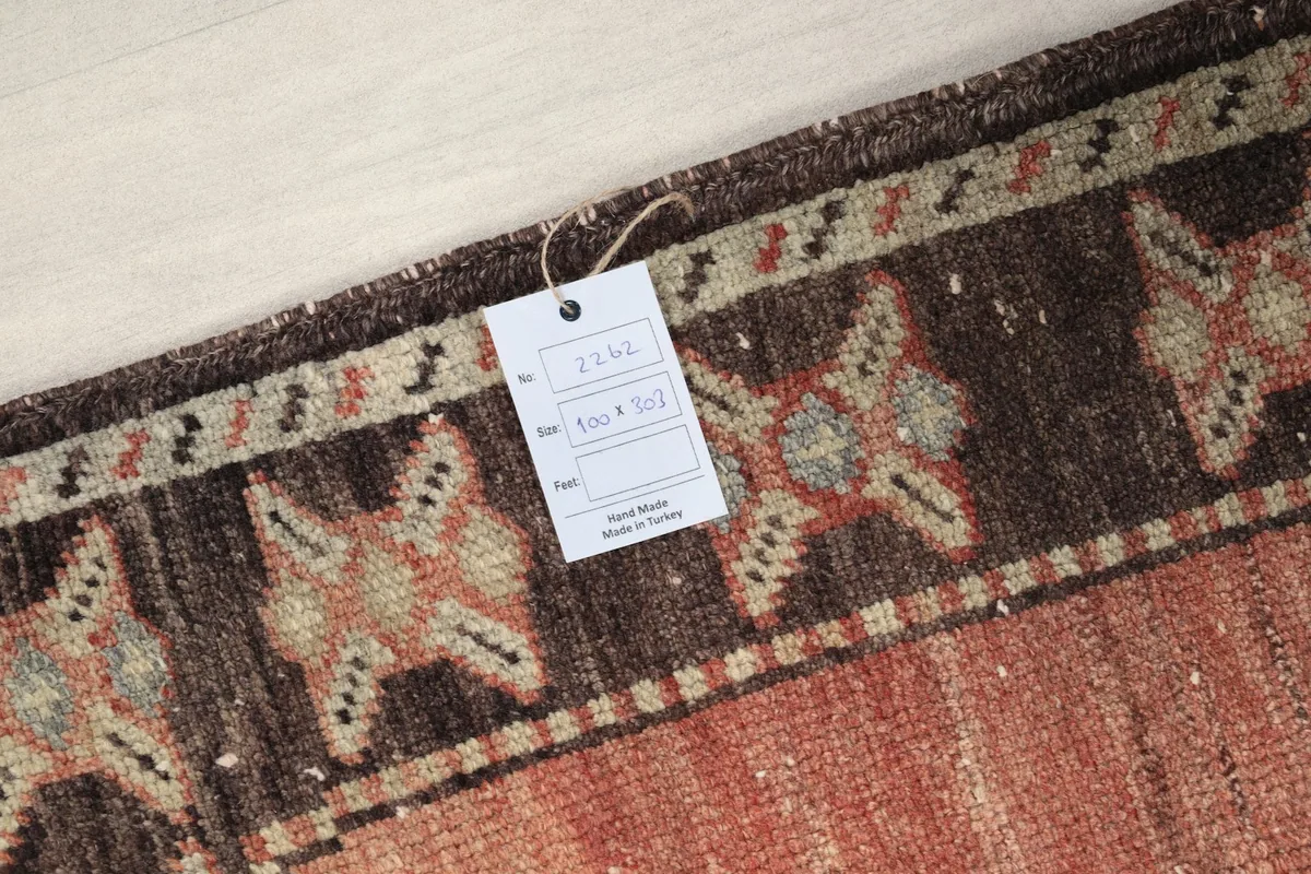 Close-up of the rug's corner with a product tag displaying size and hand-knotted details