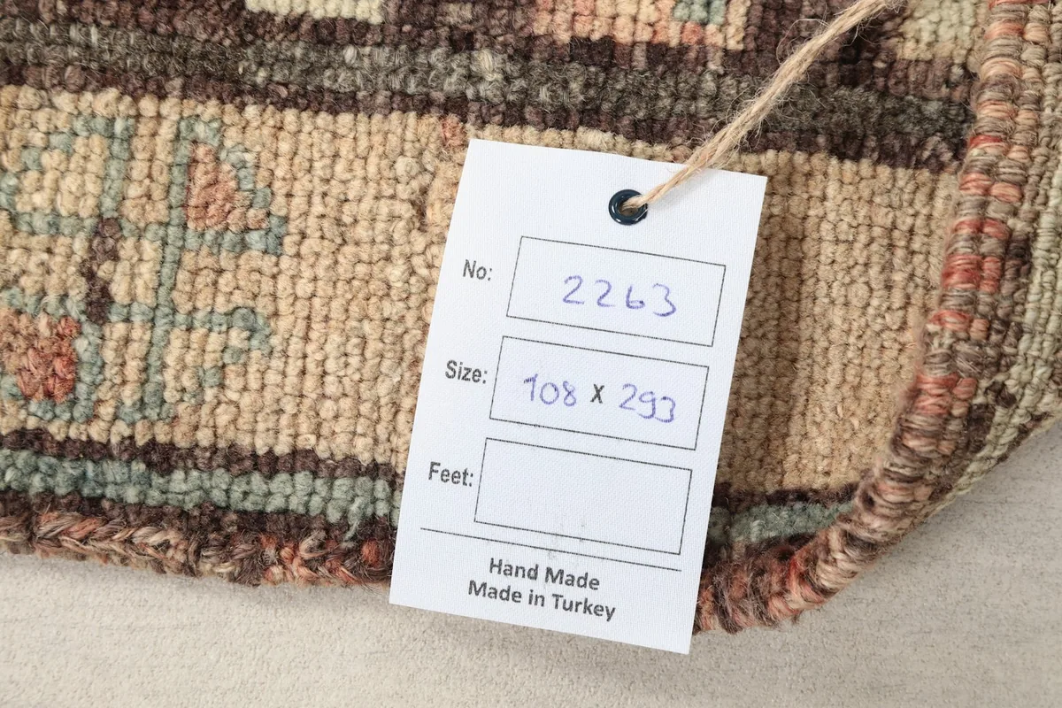 View of the rug's back and a tag showing its size 108 x 293 cm and origin.