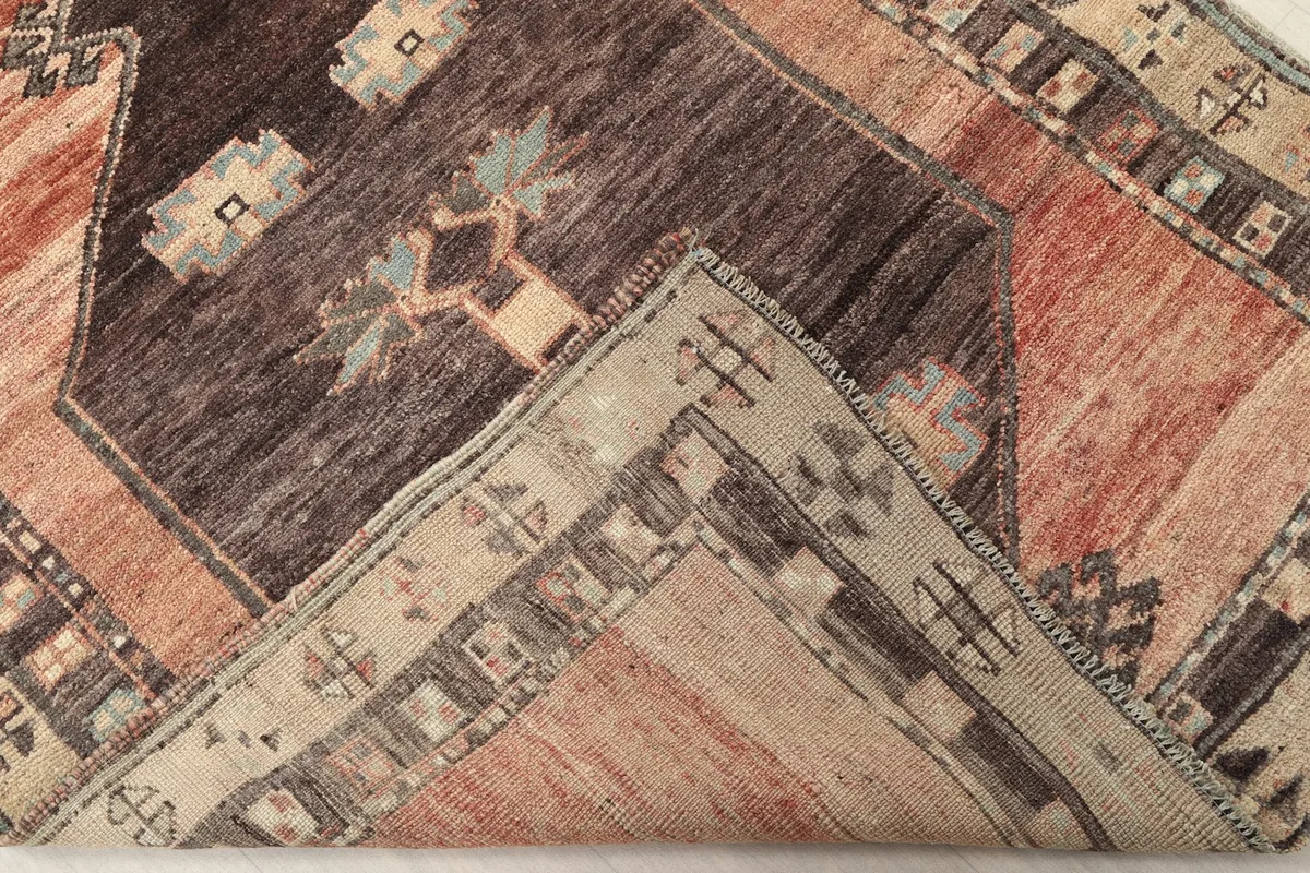 Folded corner of the rug revealing the wool pile and cotton foundation structure.