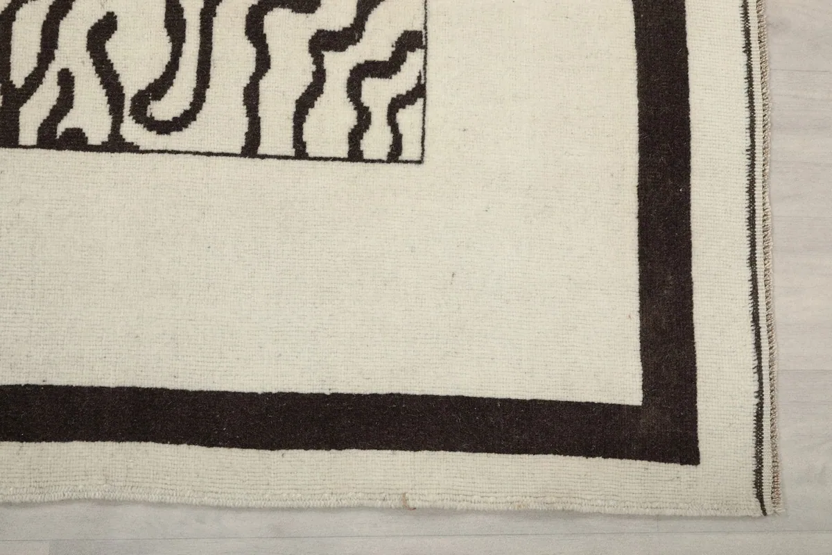 Detail of the rug's outer charcoal border and corner on the cream background