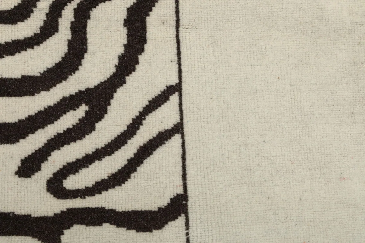 View of the low wool pile texture in both the cream and charcoal sections of the rug