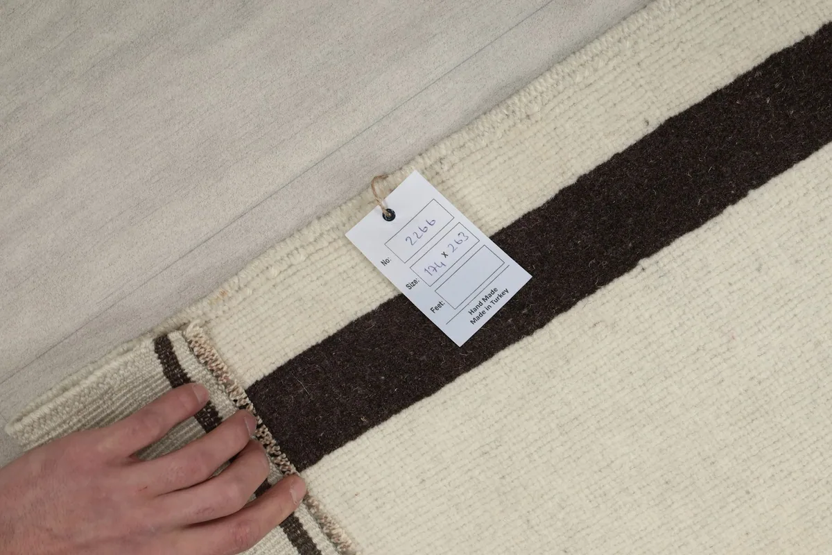 Hand holding a tag on the back of the rug, showing the size and origin details