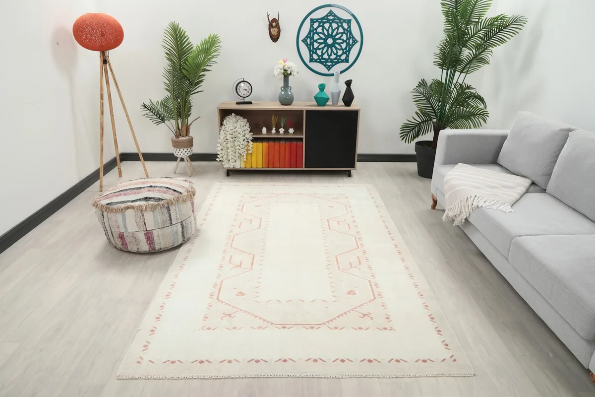 Cream and rose rug in a living room setting with a light gray couch and wooden furniture
