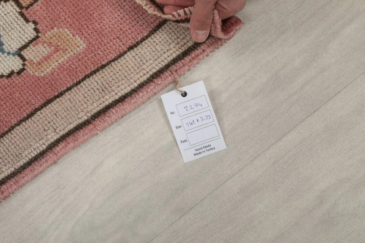 Hand holding a tag with rug information next to the rug