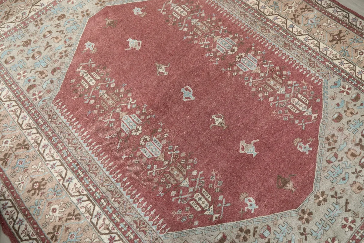 Detailed view of the rose field and some of the small blue and beige tribal motifs within the medallion