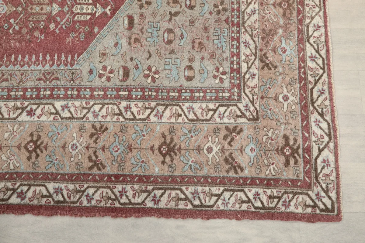 Detail view of the outer beige and brown border patterns and corner design of the rug
