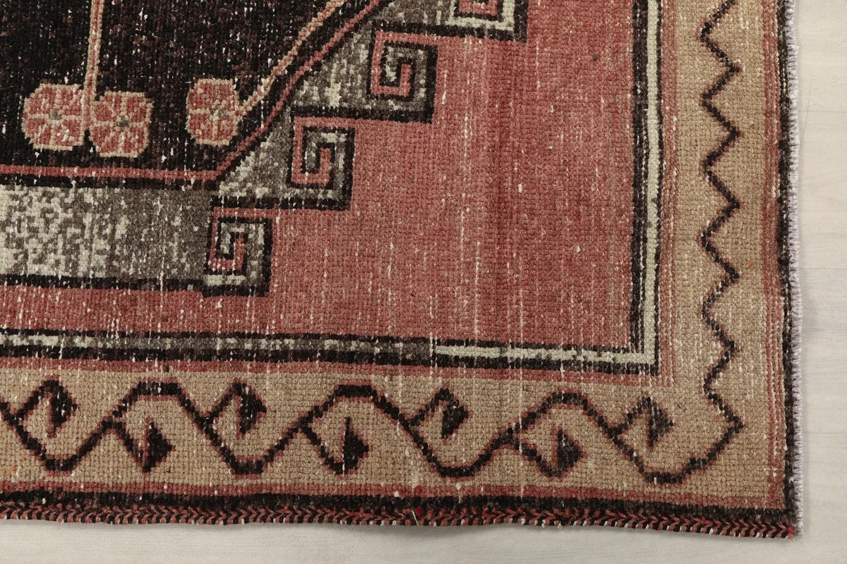 Detailed view of the rug's border pattern and a corner of the main rose field with black and beige accents.