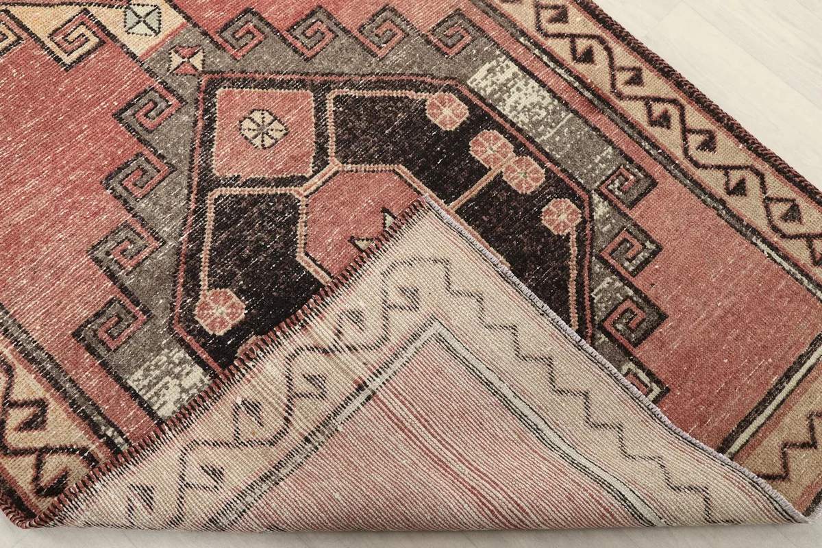 Corner of the rug folded to reveal the hand-knotted cotton foundation and the reverse side of the pile.