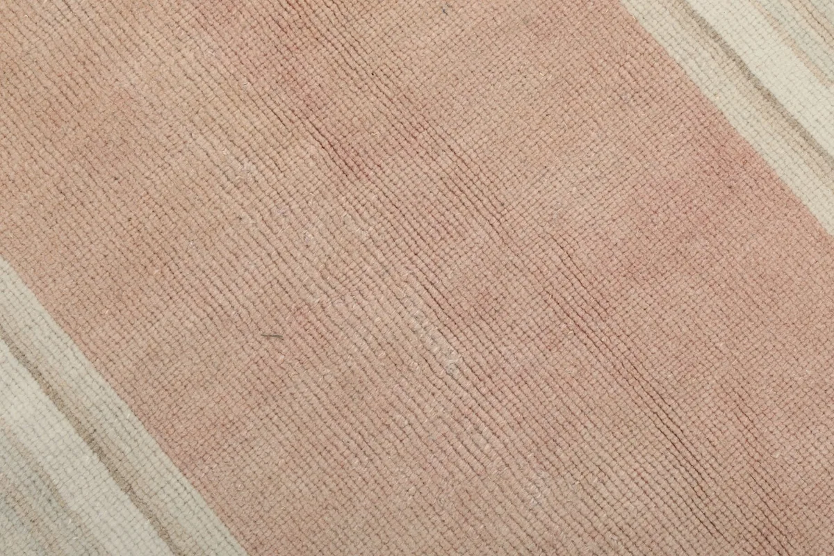 Texture detail of the low pile wool surface in a pink section of the rug