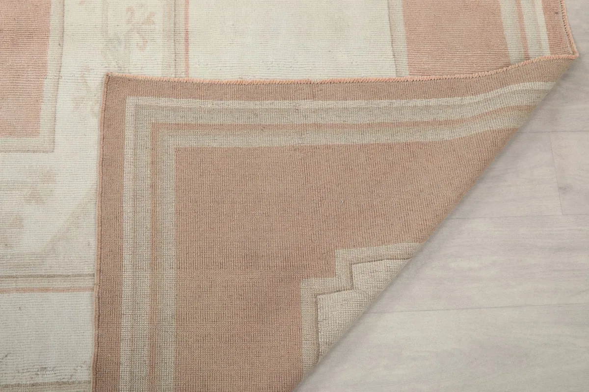 Underside of the rug at a folded corner, showing the hand-knotted cotton foundation