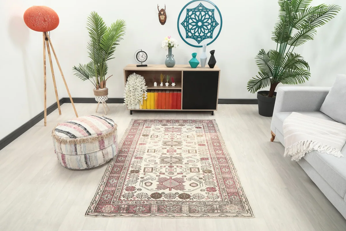 Ivory and rose rug placed in a modern living room setting with a light gray couch and wooden furniture.