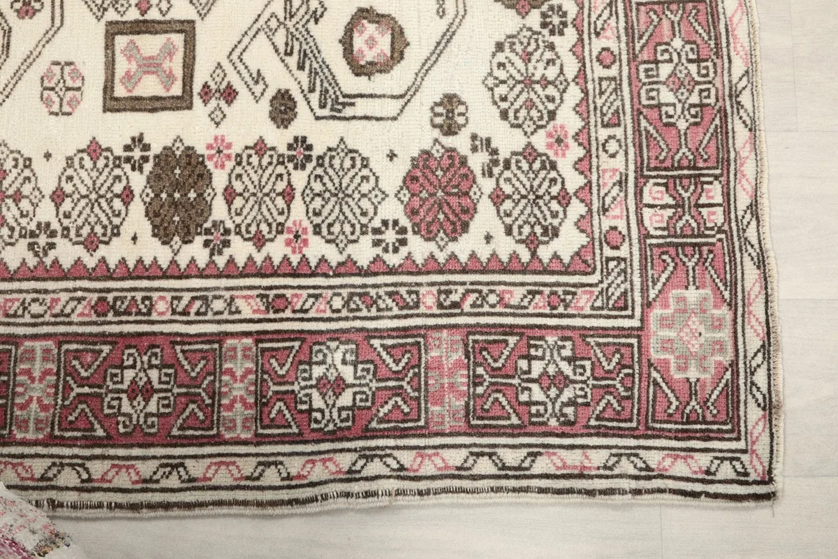 Detailed view of the rug's rose border and corner, highlighting the intricate geometric motifs.